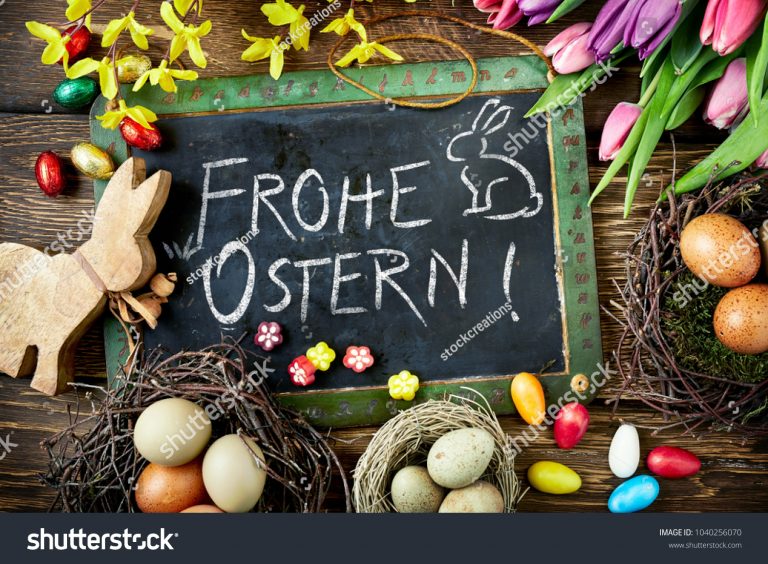 stock-photo-frohe-ostern-easter-greeting-handwritten-on-a-vintage-school-slate-surrounded-with-cute-wooden-1040256070